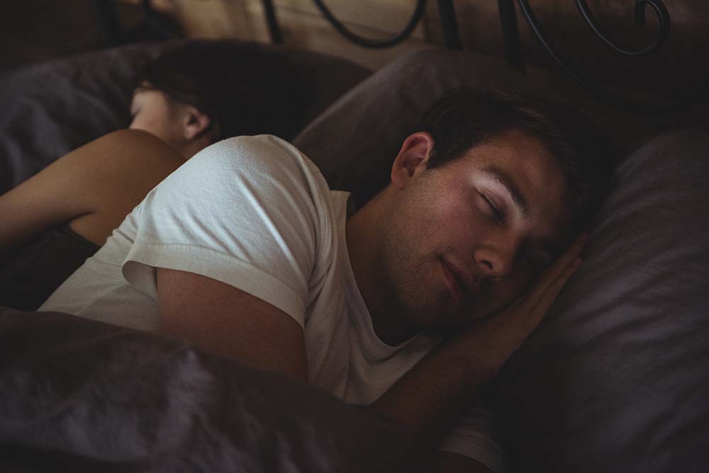 Mladý muž a žena spokojeně spí v posteli